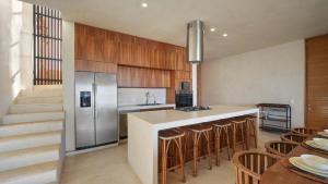 a kitchen with a counter with a refrigerator and chairs at Beachfront Villa Punta Mita Litibu in Higuera Blanca