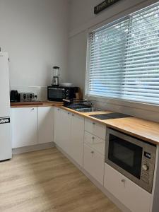 a kitchen with white cabinets and a microwave and a window at South West Rocks Gap Beach Studio in Arakoon +10 photos