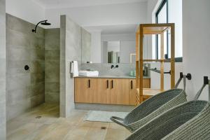 a bathroom with a shower and a sink with two chairs at The Sandpiper Escape in Broome +5 photos