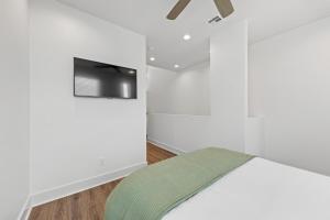 Un dormitorio con una cama y un televisor en la pared. en Boudin House Luxury Amenities Prime Location WiFi, en Lafayette