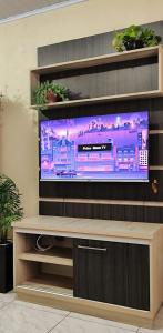 a flat screen tv sitting on top of a wooden entertainment center at Geminado 2 in Santa Cruz do Sul