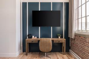 a desk with a television on a blue wall at The Skowhegan By Kasa in Skowhegan