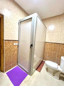 y baño con ducha, aseo y alfombra púrpura. en Family quite apart full furnished, en Oulad Akkou