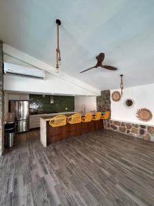 a living room with yellow chairs and a ceiling fan at Casa Madera in Acapulco