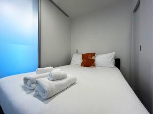 a bedroom with a large white bed with towels on it at Beautiful Apartment w sea view in Auckland +16 photos