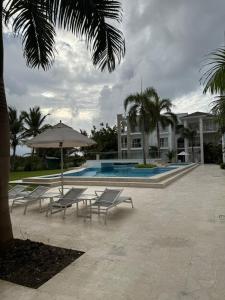 プンタ・カナにあるRelax in Cana Pearl, Punta Canaのプールサイドの椅子とパラソル