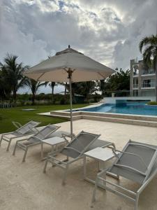 プンタ・カナにあるRelax in Cana Pearl, Punta Canaのプールサイドの椅子とパラソル