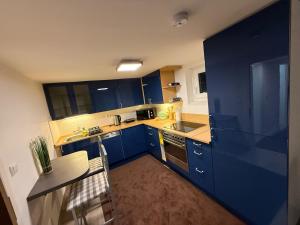 a kitchen with blue cabinets and a table and chairs at Family-friendly rental flat in Uetersen