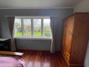 a bedroom with a large window and a wooden floor at Self check-in double or single rooms in guests house in Te Miro