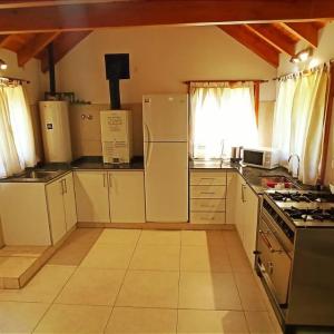 Una cocina con gabinetes blancos y un refrigerador blanco. en Cabaña Wefko - San Martin de los Andes, en San Martín de los Andes