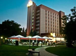 a hotel with tables and umbrellas in front of a building at Druzhba Hotel in Kryvyi Rih