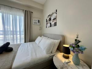 a bedroom with a bed and a table with a vase at 8F Cozy 1-Bedroom Unit The Loop Towers in Cagayan de Oro