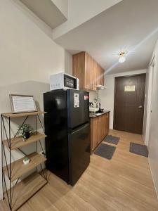 a kitchen with a black refrigerator with a microwave on top at 8F Cozy 1-Bedroom Unit The Loop Towers in Cagayan de Oro