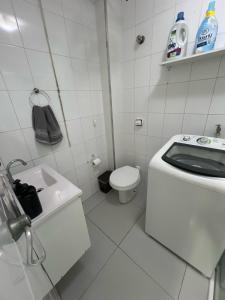 a white bathroom with a toilet and a sink at Kitnet completa com ar condicionado in São Vicente
