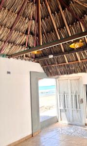 an open door to the beach with a straw roof at Villa Isla fuerte Ávila in Moñitos +10 photos