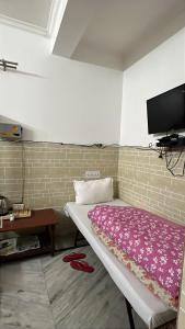 ein Zimmer mit einem Bett und einem Fernseher an der Wand in der Unterkunft Hotel dev in Dhārchula