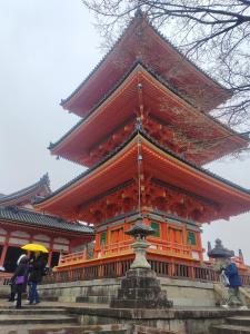 un gran edificio naranja con gente de pie delante de él en 京都四条河源町みやこ未来, en Kioto