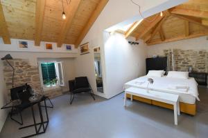 a bedroom with a white bed and a stone wall at Pylon Rooms in Split