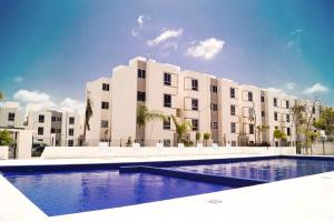 a large apartment building with a swimming pool in front of it at Departamento en Aldea Tulum in Tulum