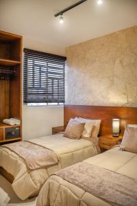 a bedroom with two beds and a window at Departamento en Aldea Tulum in Tulum +4 photos