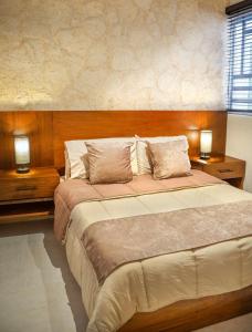 a bedroom with a large bed with two night stands at Departamento en Aldea Tulum in Tulum