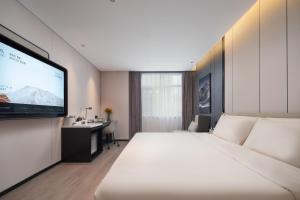 ein Hotelzimmer mit einem großen Bett und einem Flachbildfernseher in der Unterkunft Atour Hotel Dalian Xinghai Square Zhongshan Road in Dalian