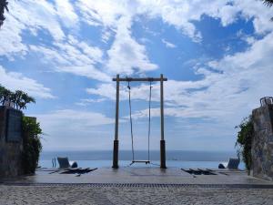 Mandala Beachfront Mui Ne - TanThanh Condotel في موي ني: أرجوحة على الشاطئ مع المحيط في الخلفية