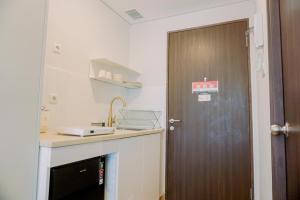 a kitchen with a brown door and a sink at Stunning Studio Transpark Bintaro Apartment By Travelio in Tangerang