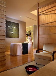 a room with a bed and a person sitting in a chair at Ningbo Portman Plaza Hotel in Ningbo