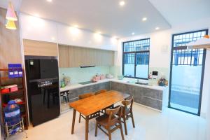 a kitchen with a wooden table and a refrigerator at KenPPi HOMESTAY - NGUYÊN CĂN, đậu nhiều xe ô tô in Hue