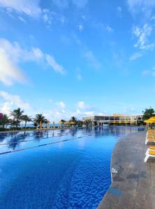 a large swimming pool with palm trees and a building at Oceanami Luxury Villa in Long Hai