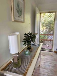 a table with a lamp and a plant on it at Bayhaven- Best deal 4 bedroom 2 bathroom getaway in Port Moonta