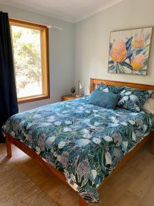 a bedroom with a bed with a blue comforter and a window at Bayhaven- Best deal 4 bedroom 2 bathroom getaway in Port Moonta