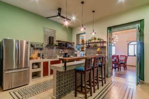 a kitchen with a refrigerator and a counter with chairs at Ya ax nah Luxury house in downtown Mérida in Mérida