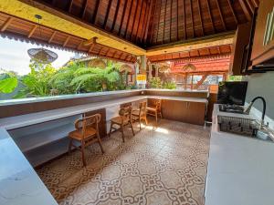 a kitchen with a bar with chairs and a desk at Swikara White House in Sukawati