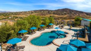 an image of a pool at a resort with blue umbrellas at Villa Inn- Adult Only- Temecula Wine Country in Temecula