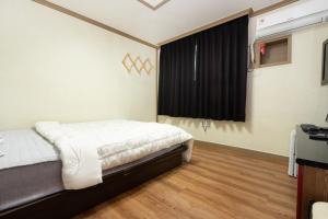 a bedroom with a bed and a window at Sangmu Green Hotel in Gwangju