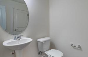 a bathroom with a sink and a toilet and a mirror at Upscale King 3BR Townhouse Mins to Cary & NC State in Raleigh