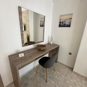 a bathroom with a vanity with a mirror and a chair at R&T Apartments in Kallithea Halkidikis