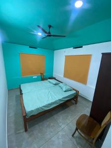 a bedroom with a bed and a ceiling fan and a chair at CanWas Rajagiri in Ernakulam