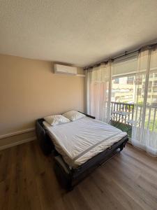 a bed in a room with a large window at Studio Le saint Clair centre port in Cap d'Agde