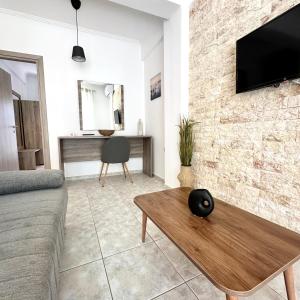 a living room with a couch and a tv on a brick wall at R&T Apartments in Kallithea Halkidikis
