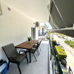 a patio with a wooden table and chairs on a balcony at R&T Apartments in Kallithea Halkidikis