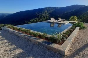 a swimming pool with two benches on top of a mountain at Blue Sky Lodge in Nicoya