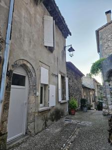 an old stone building with a white door and windows at maison de village meublée avec terrasse in Donzère