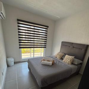 ein Schlafzimmer mit einem Bett und einem großen Fenster in der Unterkunft Comodo departamento en Barra Vieja Acapulco in Acapulco + 5 Fotos