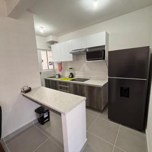 eine Küche mit einem schwarzen Kühlschrank und weißen Schränken in der Unterkunft Comodo departamento en Barra Vieja Acapulco in Acapulco