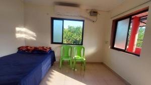 a room with two green chairs and a bed at DAKWE COTTAGe in Nagaon