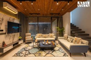 a living room with two couches and a tv at StayVista at Palm Tree Breeze with Pool, BBQ, Bonfire in Jaipur