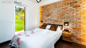 a bedroom with a brick wall and a bed at Wonder Home Myśliwska - Domki przy stoku Karpatka - na terenie kompleksu plac zabaw, zewnętrzna siłownia i sklep in Karpacz